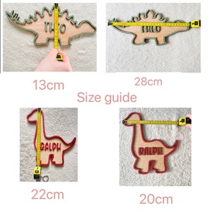 May include: Size guide for wooden dinosaur name plaques. The plaques are available in two styles: a green stegosaurus with the name "Theo" and a red brachiosaurus with the name "Ralph". The plaques measure 13 cm by 28 cm, 22 cm by 20 cm.