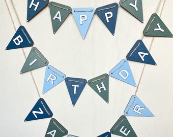 May include: A two-tiered birthday banner featuring triangular wooden pennants in shades of blue and green. Each pennant displays a single white letter, spelling out HAPPY BIRTHDAY ZAVEER. The pennants are strung together with natural twine.