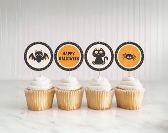 May include: Four cupcakes topped with Halloween-themed decorations. Each cupcake has a round topper with a different design: a bat, the words "Happy Halloween", a black cat, and a spider. The toppers are on white sticks.