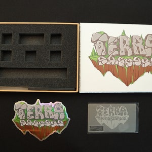 Pode incluir: Uma caixa de produto com inser&ccedil;&otilde;es de espuma, um cart&atilde;o impresso, um adesivo hologr&aacute;fico e um cart&atilde;o impresso. A caixa e os cart&otilde;es apresentam o texto "TERRA KEYCAPS" em uma fonte estilizada, com um gr&aacute;fico de ilha flutuante.