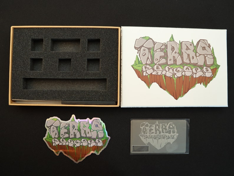 Pode incluir: Uma caixa de produto com inser&ccedil;&otilde;es de espuma, um cart&atilde;o impresso, um adesivo hologr&aacute;fico e um cart&atilde;o impresso. A caixa e os cart&otilde;es apresentam o texto "TERRA KEYCAPS" em uma fonte estilizada, com um gr&aacute;fico de ilha flutuante.