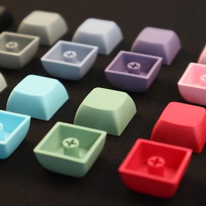 May include: A collection of colorful keycaps in various shades of blue, green, pink, red, and orange. The keycaps are made of plastic and have a smooth, glossy finish.