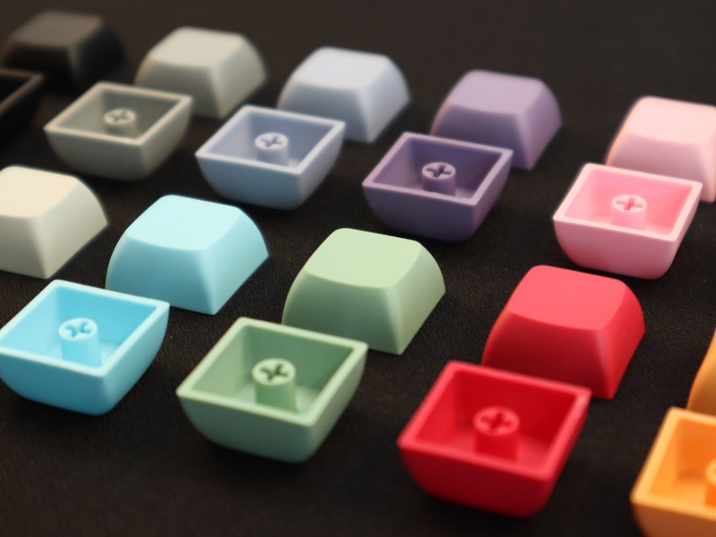 May include: A collection of colorful keycaps in various shades of blue, green, pink, red, and orange. The keycaps are made of plastic and have a smooth, glossy finish.