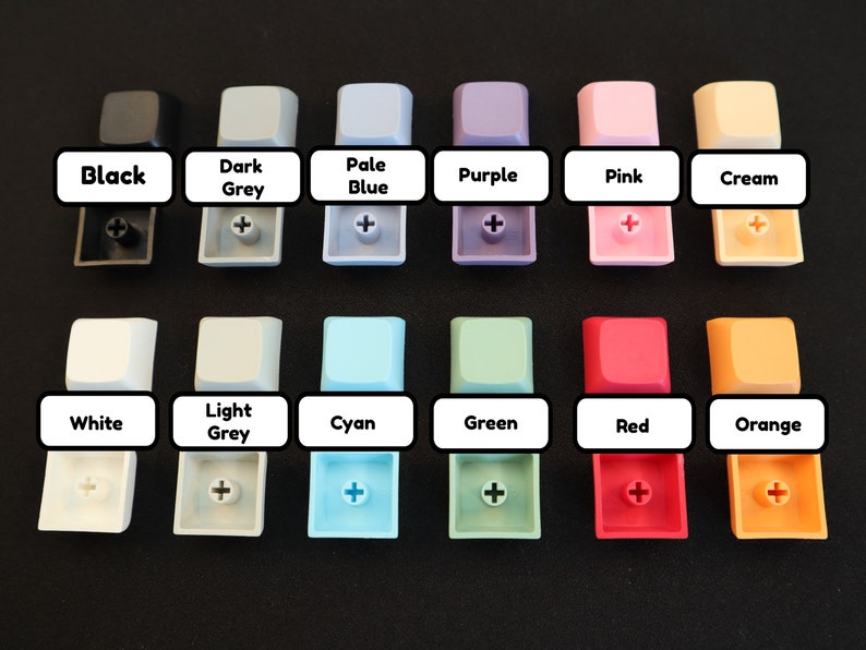 May include: A set of 12 keycaps in various colors, including black, white, light grey, dark grey, pale blue, cyan, green, purple, pink, cream, red, and orange. Each keycap has a plus sign printed on it.