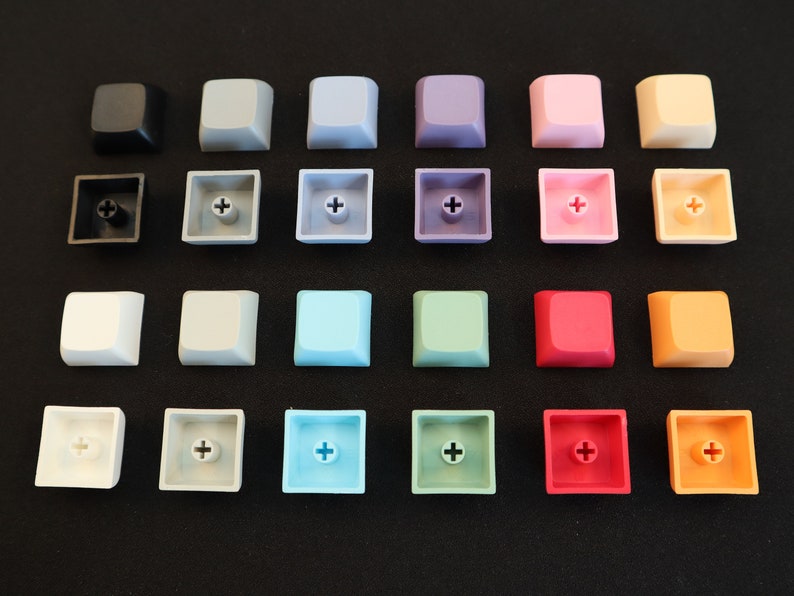 May include: A set of 18 keycaps in various colors, including black, white, gray, blue, green, pink, red, and yellow. Each keycap has a plus sign printed on it.