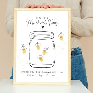 May include: A framed print with a light wood frame. The artwork features a jar with fireflies and the text "Happy Mother's Day." Below the jar is the text "Thank you for always shining Jesus' light for me!"