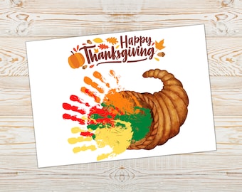May include: A Thanksgiving-themed craft project with a cornucopia filled with colorful handprints. The handprints are in shades of red, orange, yellow, and green. The text "Happy Thanksgiving" is written in brown lettering above the cornucopia.