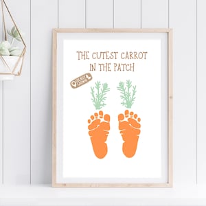 May include: A white framed print with the text "The Cutest Carrot in the Patch" and a brown stamp that says "Locally Grown". Two orange baby footprints are printed below the text, with green carrot tops above each footprint.