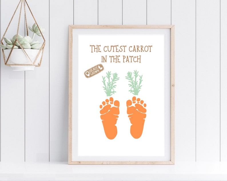 May include: A white framed print with the text "The Cutest Carrot in the Patch" and a brown stamp that says "Locally Grown". Two orange baby footprints are printed below the text, with green carrot tops above each footprint.