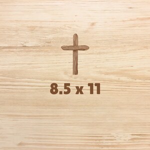 May include: A wooden cross on a light brown wood background with the text "8.5 x 11" below it.