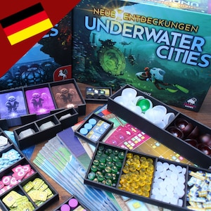 Op de afbeelding: Een spelorganizer voor het bordspel "Underwater Cities: Neue Entdeckungen". De organizer is gemaakt van zwart plastic en heeft compartimenten voor alle spelonderdelen, inclusief het bord, tegels, meeples en tokens. De organizer wordt getoond op een tafel met de doos van het spel op de achtergrond.