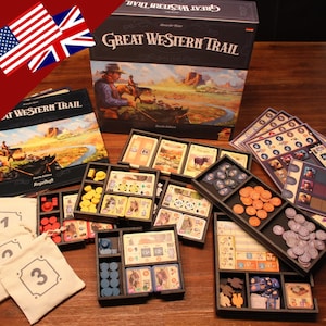 Könnte beinhalten: Ein Spielbrett und Spielfiguren für das Brettspiel Great Western Trail. Das Spielbrett ist braun mit einem Bild eines Cowboys, der ein Pferd reitet. Die Spielfiguren sind aus Holz und Plastik. Das Spiel spielt im amerikanischen Westen.