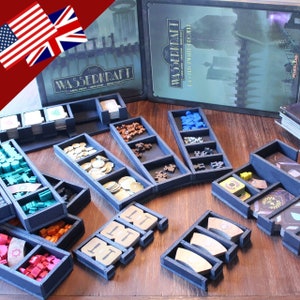 Könnte beinhalten: Ein Satz schwarzer Schaumstoffeinsätze zum Organisieren von Spielsteinen. Die Einsätze sind für das Brettspiel "Wasserkraft: The City Will Grow" konzipiert. Die Einsätze sind mit verschiedenen Spielsteinen gefüllt, darunter Münzen, Spielmarken und Karten.