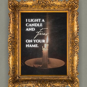 Puede incluir: Impresión enmarcada con un marco dorado ornamentado. La impresión presenta una vela encendida sobre un fondo oscuro con el texto "I LIGHT A CANDLE AND focus ON YOUR NAME."