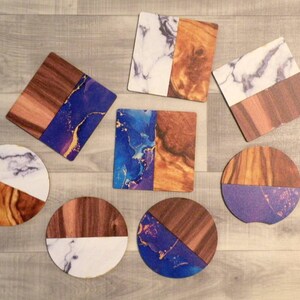 May include: Eight coasters with a wood and marble design. The coasters feature a variety of marble patterns, including white and gray, blue and gold, and purple and gold. The wood is a dark brown color.