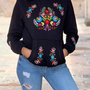 May include: Black hooded sweatshirt with colorful floral embroidery on the front and sleeves. The embroidery features a variety of flowers in pink, blue, yellow, and green.