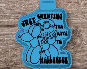 May include: Blue plastic cookie cutter shaped like a skeleton holding a balloon with the text "Just counting the days to Halloween".
