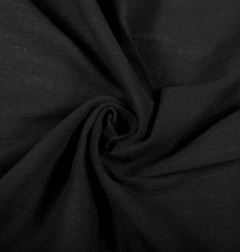 May include: A solid black fabric with a soft, matte texture, featuring deep, swirling folds and natural drapes that create a series of shadows and highlights across the surface, emphasising the consistent dark colour and the pliable nature of the material.