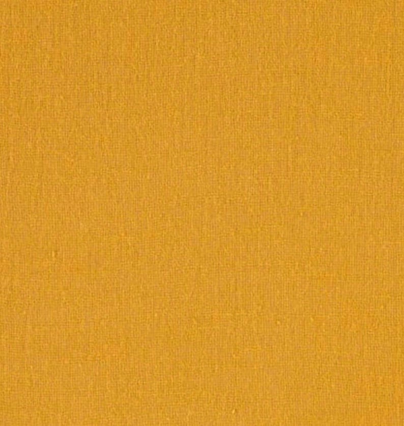 May include: A solid mustard yellow fabric with a visible woven texture. The material displays a consistent, uniform colour throughout, featuring a fine, interlaced thread pattern that creates a subtle, tactile surface appearance across the entire frame.