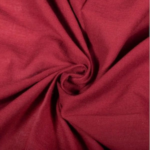 May include: A deep burgundy fabric with a soft, matte texture, featuring natural folds and creases that create a dynamic play of light and shadow across the surface. The material appears lightweight and flexible, showing a consistent solid colour.