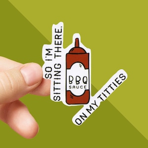 May include: A white sticker with a brown BBQ sauce bottle illustration and the text "BBQ SAUCE". The sticker also has the phrases "SO I'M SITTING THERE." and "ON MY TITTIES" in white text.