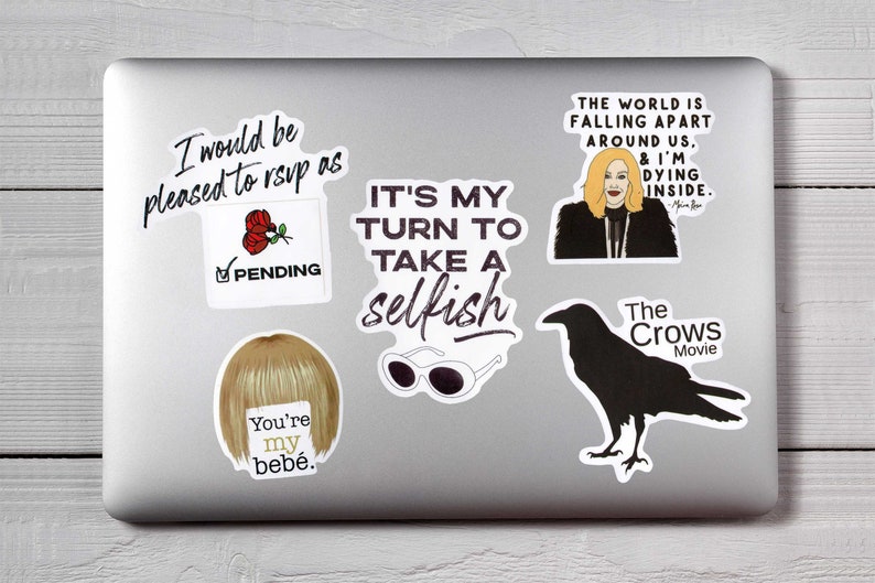 May include: A collection of stickers on a laptop. The stickers feature various designs, including text like "I would be pleased to rsvp as", "It's my turn to take a selfish", and "The world is falling apart around us, & I'm dying inside."
