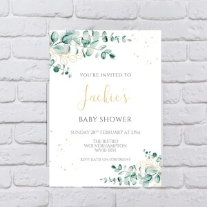 May include: A white baby shower invitation with gold lettering and a watercolor illustration of eucalyptus leaves. The invitation reads "You're invited to Jackie's Baby Shower, Sunday 28th February at 2pm, The Bistro, Wolverhampton, WV10 5TH, RSVP: Katie on 07807861345."