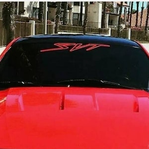 May include: A red sports car with a black windshield and a red "SVT" decal on the windshield.