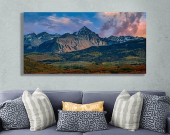 Könnte beinhalten: Ein Panoramafoto einer Bergkette mit einem rosa und blauen Himmel. Die Berge sind mit Bäumen und Schnee bedeckt. Der Himmel ist voller Wolken.