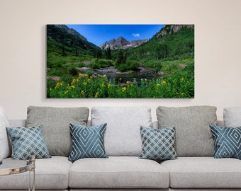 Puede incluir: Una fotografía panorámica de un paisaje de valle de montaña con un pequeño lago en primer plano. Las montañas están cubiertas de exuberantes árboles verdes y el lago está rodeado de flores silvestres amarillas.