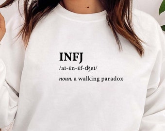 May include: White sweatshirt with black text that reads "INFJ /ar-en-ef-dzer/ noun. a walking paradox".