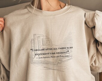 May include: A beige sweatshirt with a quote from Jane Austen's Pride and Prejudice printed on the front. The quote reads, "I declare after all there is no enjoyment like reading!" The quote is surrounded by a drawing of a stack of books.
