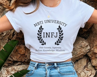 Pode incluir: Camiseta branca com o texto "MBTI University" e uma coroa de louro com as letras "INFJ" dentro. O texto abaixo da coroa diz "Ante Scientia, Sapientia Before Knowledge, Wisdom".