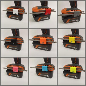 K&ouml;nnte beinhalten: Nahaufnahme eines Akkupacks f&uuml;r eine Bohrmaschine mit einem daran befestigten Bit-Halter. Der Bit-Halter ist in verschiedenen Farben erh&auml;ltlich, darunter Wei&szlig;, Rot, Schwarz, Orange, Pink, Blau und Gelb. Der Akkupack tr&auml;gt den Aufdruck "MAX 4Ah".