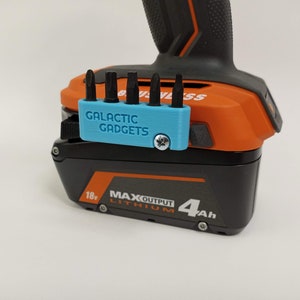 May include: A blue 3D printed bit holder with the text "GALACTIC GADGETS" attached to a black and orange power tool battery. The battery is labeled "18v MAX OUTPUT LITHIUM 4Ah".