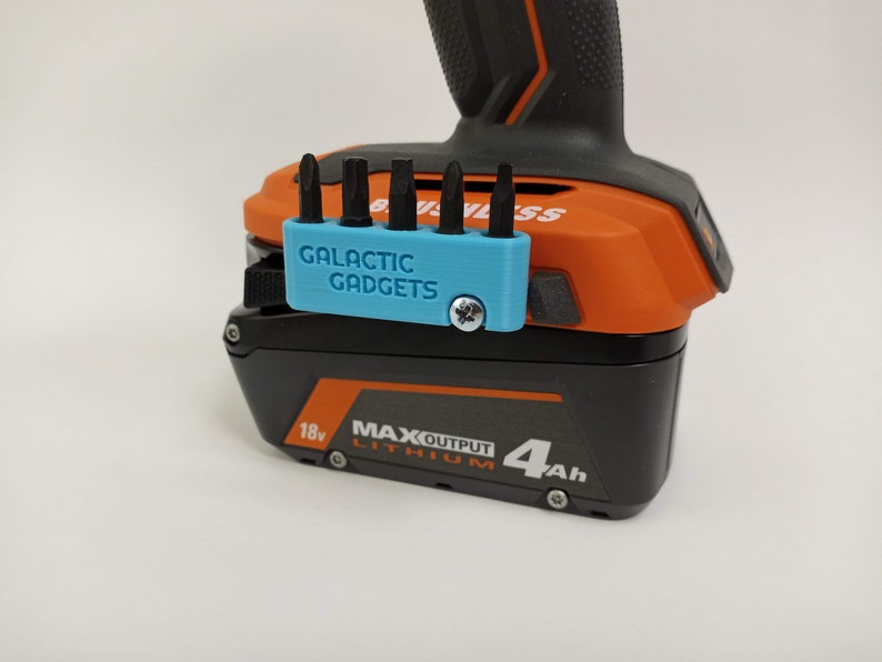 May include: A blue 3D printed bit holder with the text "GALACTIC GADGETS" attached to a black and orange power tool battery. The battery is labeled "18v MAX OUTPUT LITHIUM 4Ah".