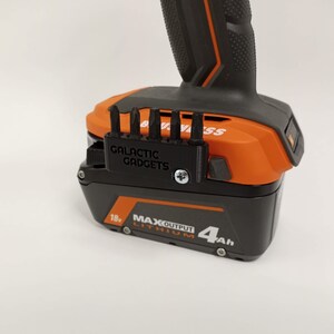 May include: A black 3D printed bit holder with the text "GALACTIC GADGETS" attached to an orange and black power tool battery. The battery is labeled "18v MAX OUTPUT LITHIUM 4Ah".