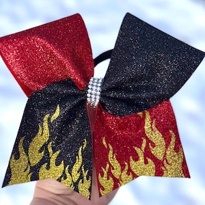 May include: A red and black cheer bow with gold glitter flames and a rhinestone center.
