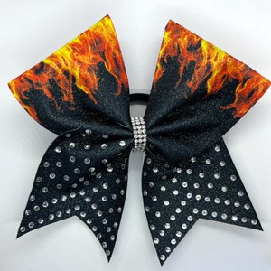 May include: Black cheer bow with a flame design and silver glitter. The bow is decorated with clear rhinestones.