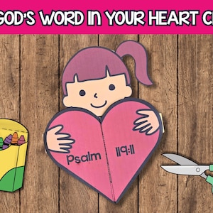 Puede incluir: Un proyecto de manualidades con el texto "HIDE GOD'S WORD IN YOUR HEART CRAFT". El proyecto incluye una niña sosteniendo un corazón rosa con "salmo 119:11" impreso, una caja de crayones y tijeras.