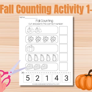 May include: A fall-themed educational worksheet with the text "Fall Counting Activity 1-10." The worksheet features illustrations of pumpkins, leaves, and other fall elements. A pair of scissors and a hand are visible, suggesting a cutting activity. A pumpkin is in the lower right corner.
