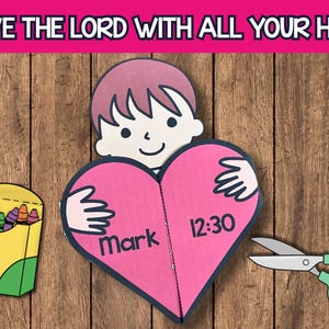 Puede incluir: Un proyecto de manualidades colorido con un recorte de papel de un niño abrazando un corazón rosa con el texto "Mark 12:30". También hay una caja de crayones y tijeras verdes. Las palabras "LOVE THE LORD WITH ALL YOUR HEART" están en la parte superior.