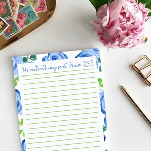 May include: A white lined notepad with a blue floral border and the text "He restoreth my soul" Psalm 23:3. The notepad has a green line pattern.