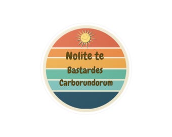 Puede incluir: Una pegatina redonda con un diseño de puesta de sol retro. La pegatina presenta un sol sonriente y el texto "Nolite te Bastardes Carborundorum".