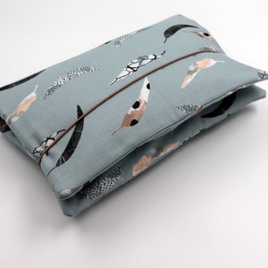 May include: A light blue fabric clutch with a brown strap and a pattern of abstract shapes in black, white, and pink.