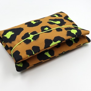 May include: A brown and black leopard print fabric pouch with a bright green elastic band.