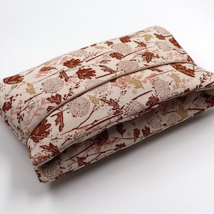 Pode incluir: Uma carteira de tecido bege com um padrão floral castanho. A carteira tem um fecho de correr castanho e um forro de tecido castanho.