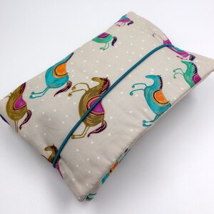 May include: A beige fabric pouch with a teal elastic closure. The pouch is decorated with a repeating pattern of colorful horses on a white background with small white dots.