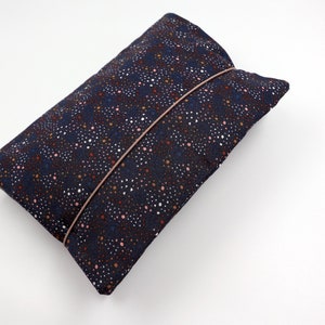 May include: A dark blue fabric pouch with a pink and brown polka dot pattern. The pouch has a pink elastic band closure.