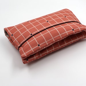 May include: A red and white checkered fabric pouch with black dots and a black elastic band.